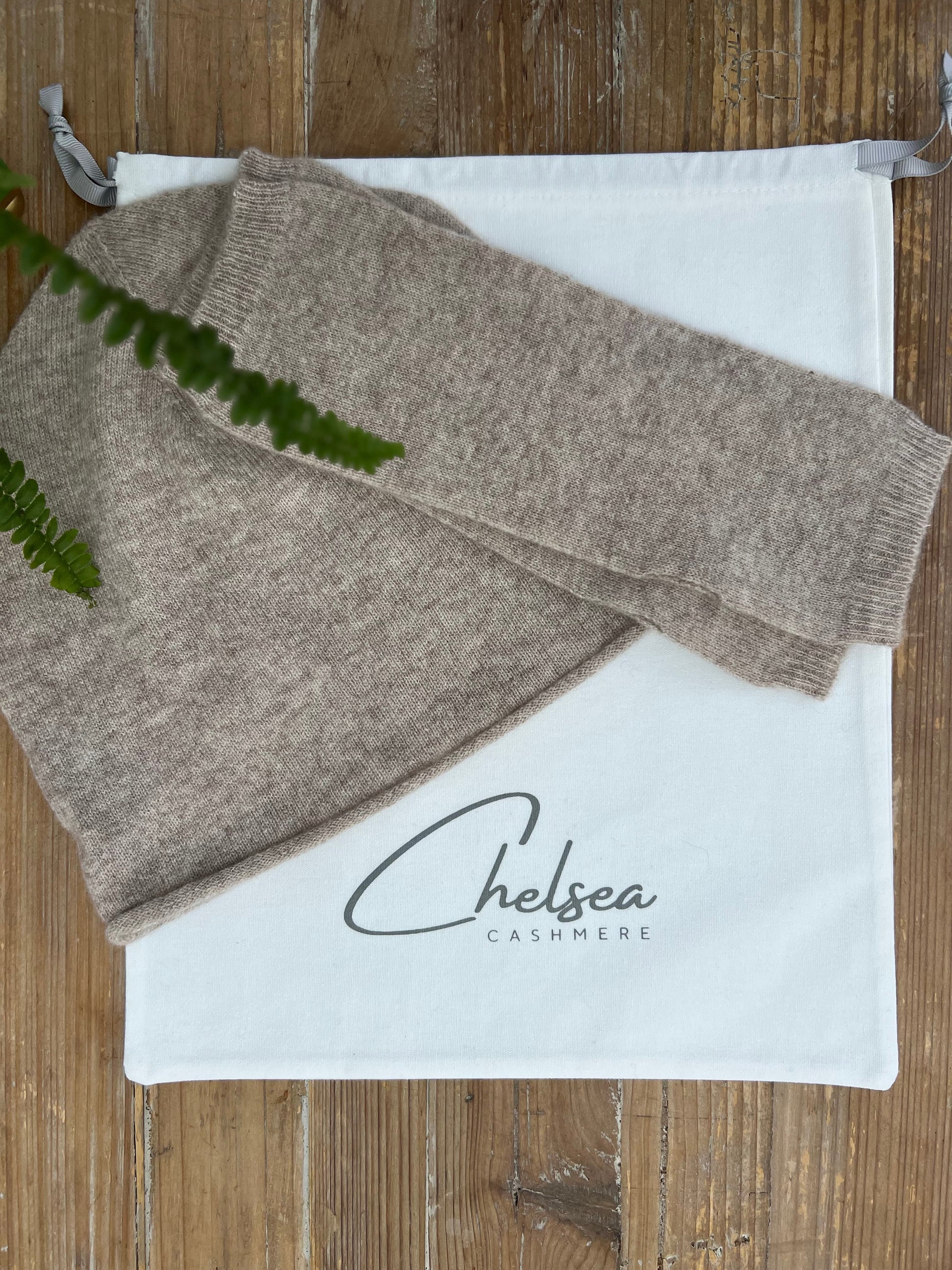 Brown cashmere hat and wrist warmers 
on a white Chelsea Cashmere bag on a wooden surface