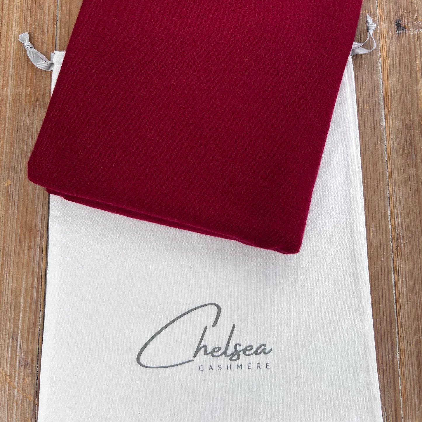 Red cashmere scarf on a white Chelsea Cashmere dust bag 