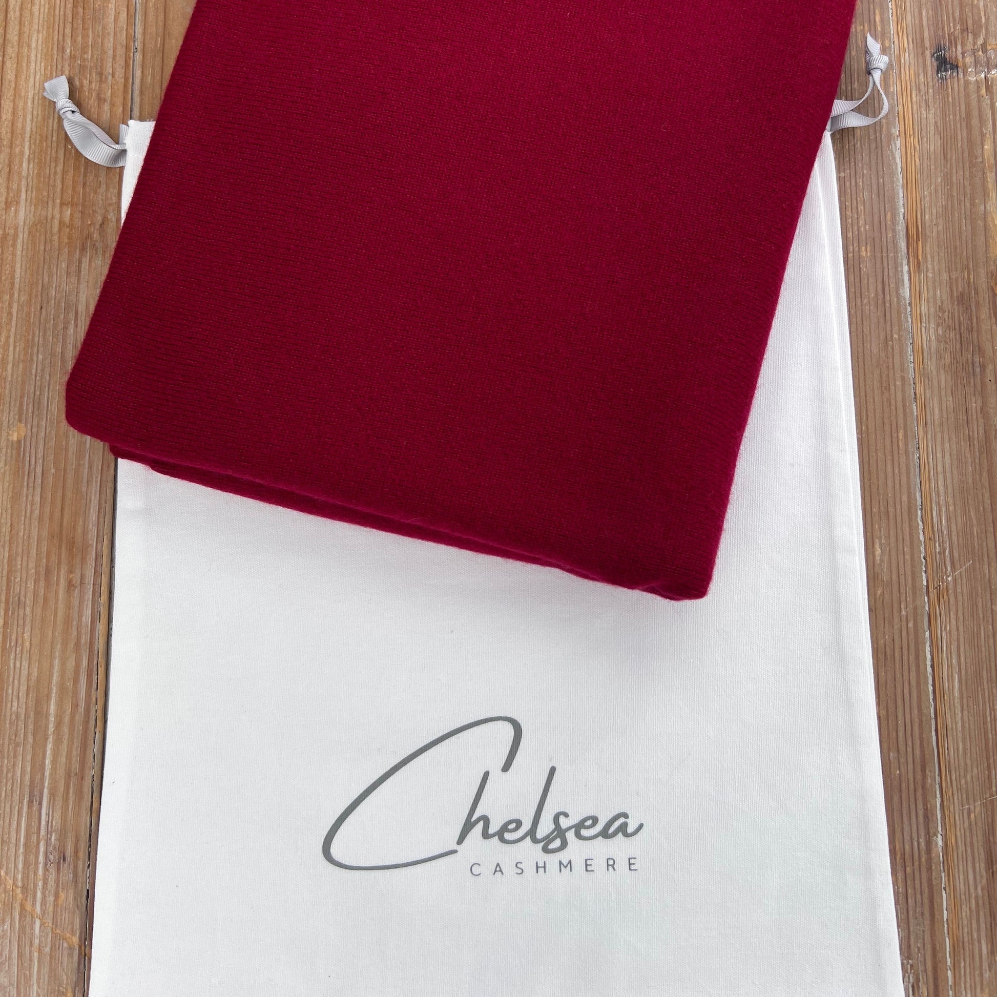 Red cashmere scarf on a white Chelsea Cashmere dust bag 