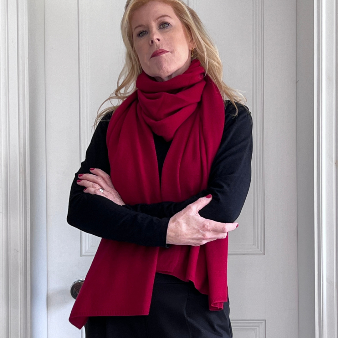 Woman wearing a red cashmere scarf and smart black outfit.