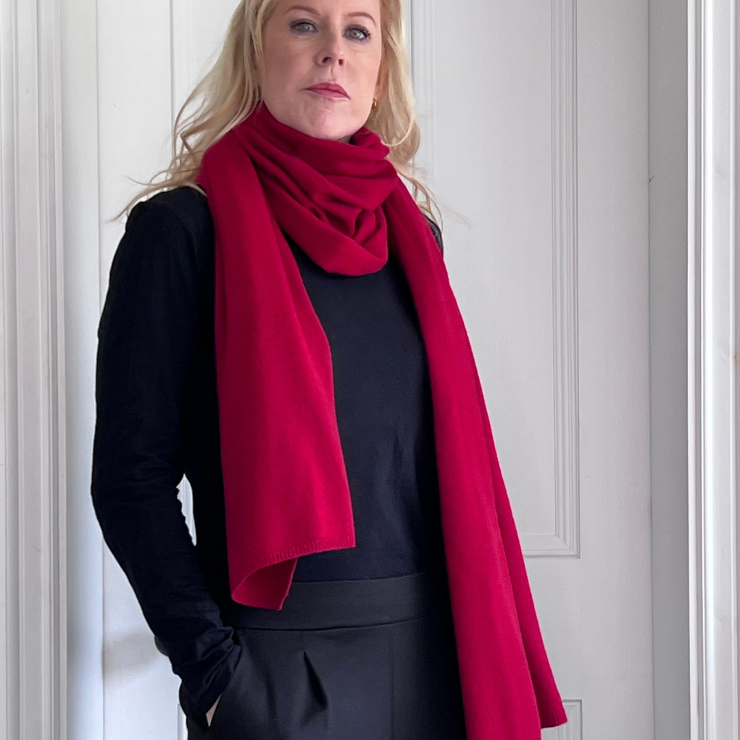 Woman wearing a red cashmere scarf and black top and trousers