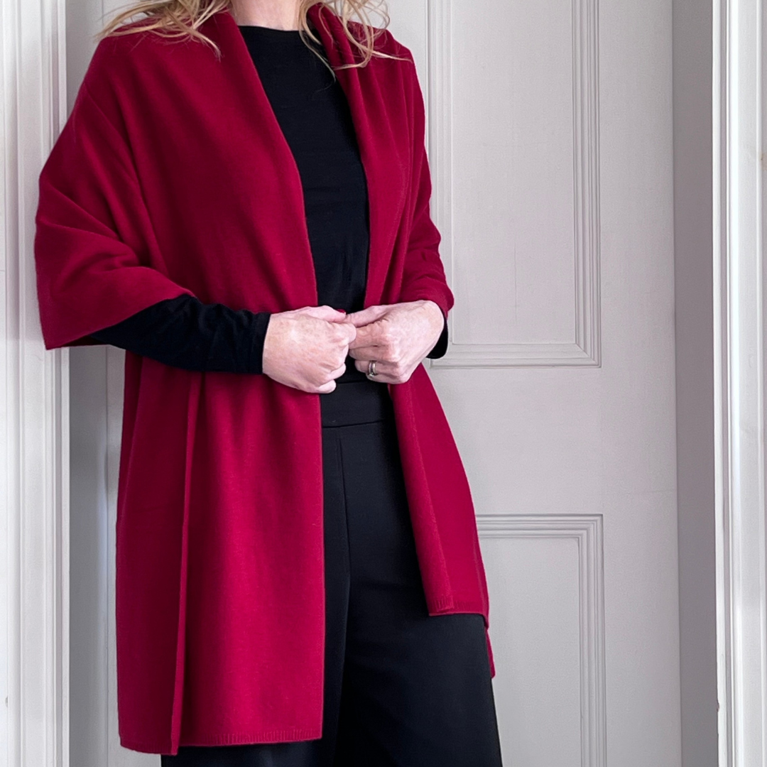 Woman wearing a red cashmere wrap over a black top and trouserss 