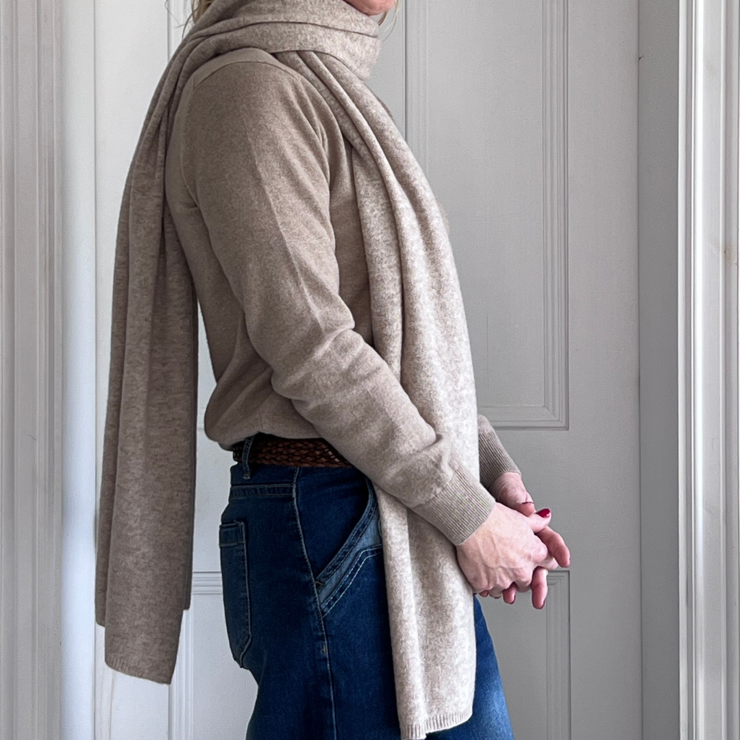 Woman wearing a beige cashmere scarf and sweater with jeans.