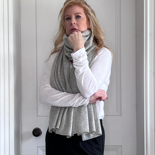 Woman wearing a grey cashmere scarf and white long-sleeve shirt and black trousers