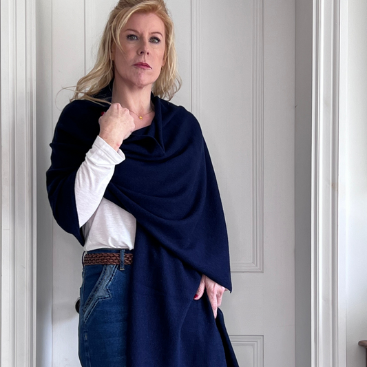 Woman wearing a navy blue cashmere shawl over a white shirt and jeans.