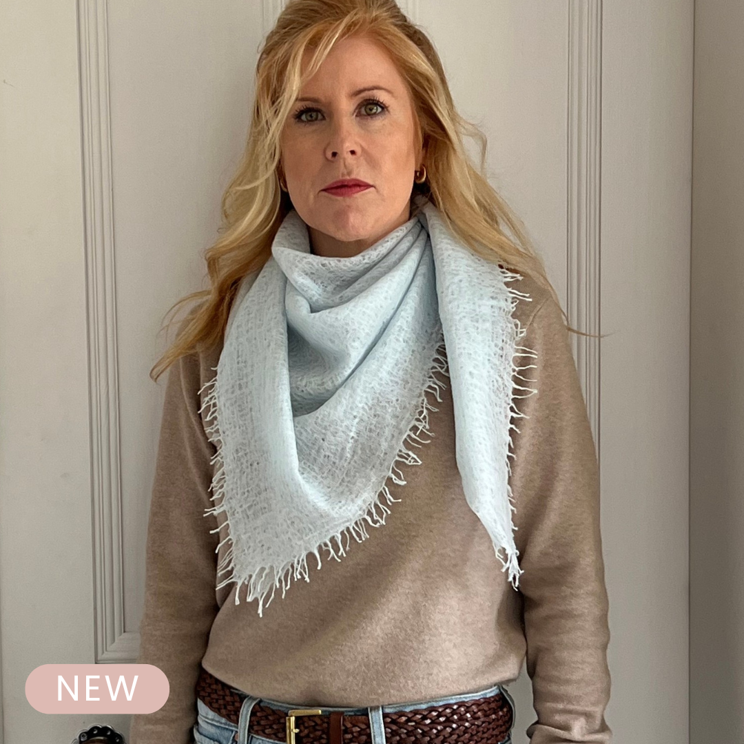 Woman wearing a light blue cashmere scarf with a neutral background