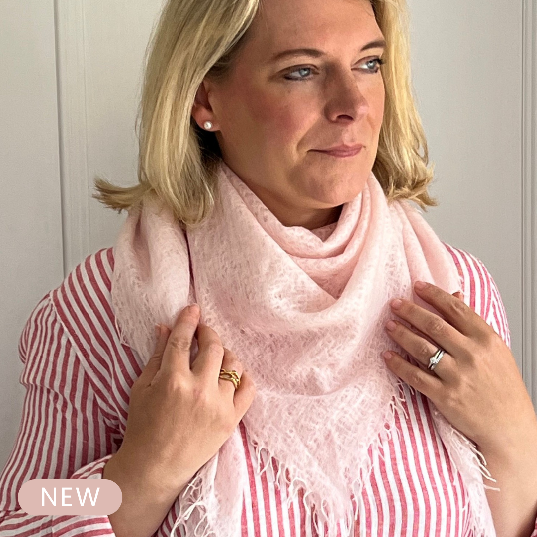 Woman wearing a lightweight pink cashmere scarf with a white background