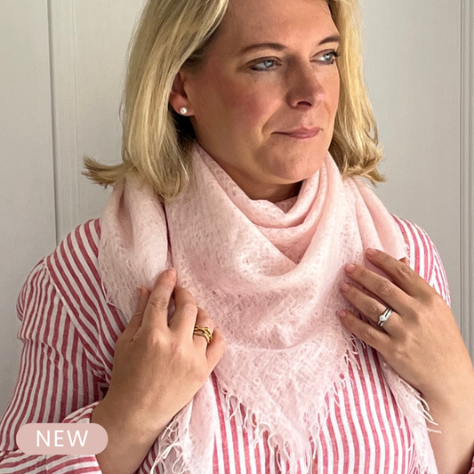 Woman wearing a lightweight pink cashmere scarf with a white background