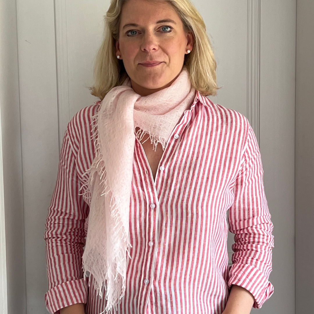 Woman wearing a red and white striped shirt with a pink cashmere scarf against a neutral background