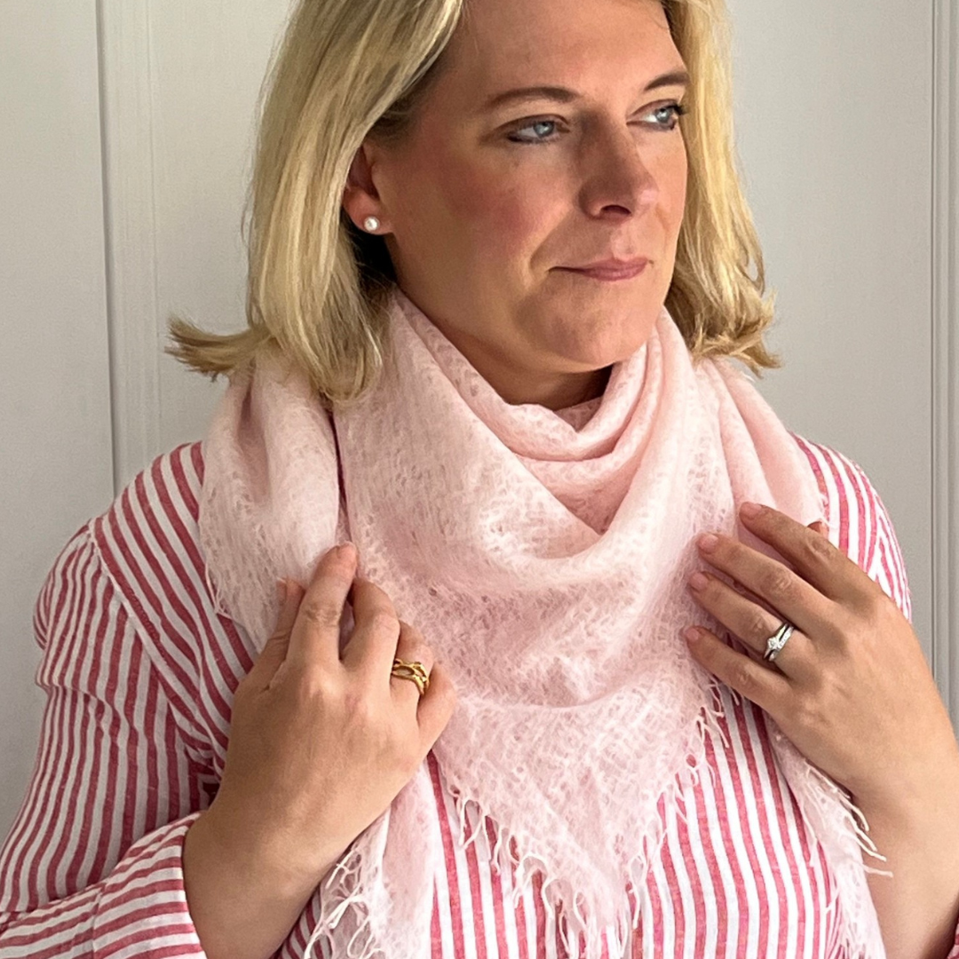 Woman wearing a pink woven cashmere scarf with a white background